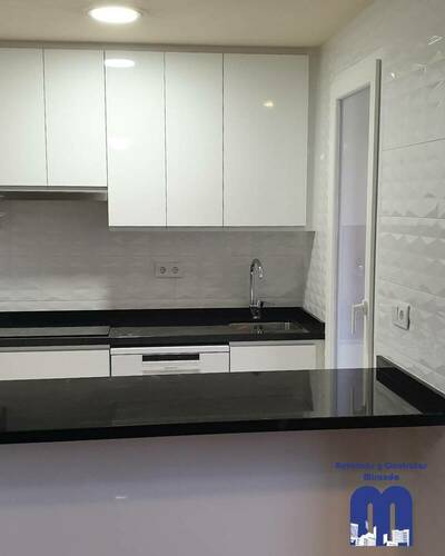 Cocina moderna y luminosa con barra abierta al salón tras una reforma completa.
