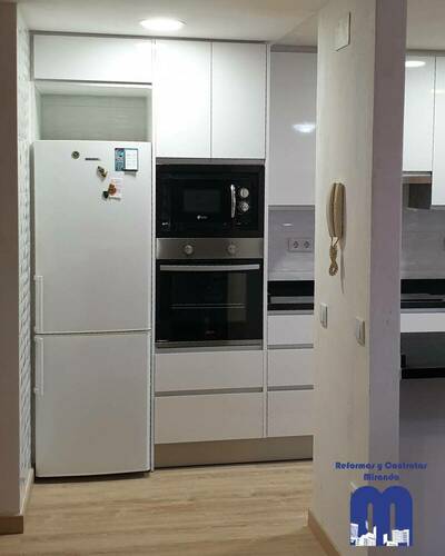Cocina moderna y luminosa con barra abierta al salón tras una reforma completa.