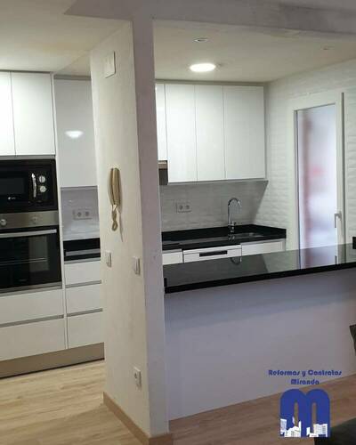 Cocina moderna y luminosa con barra abierta al salón tras una reforma completa.