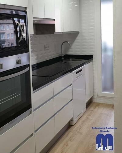 Cocina moderna y luminosa con barra abierta al salón tras una reforma completa.