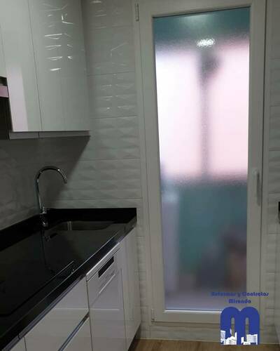 Cocina moderna y luminosa con barra abierta al salón tras una reforma completa.