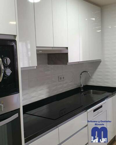 Cocina moderna y luminosa con barra abierta al salón tras una reforma completa.