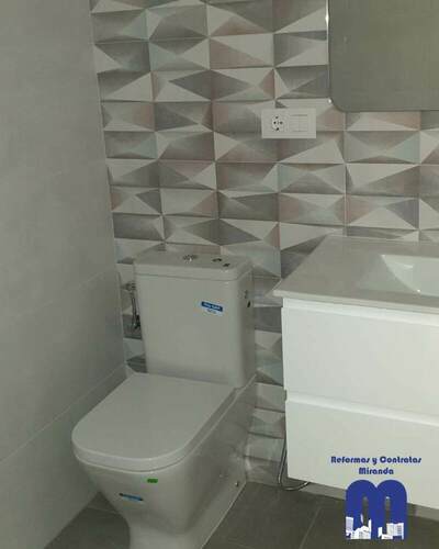 Baño reformado con diseño actual, revestimiento geométrico, ducha con mampara de cristal y mobiliario suspendido, pensado para ofrecer funcionalidad, luminosidad y un estilo contemporáneo.