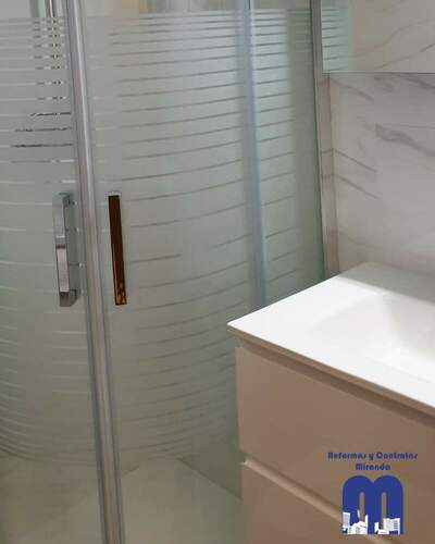 Reforma integral de baño moderno con ducha curva y revestimiento efecto mármol