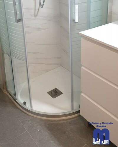 Reforma integral de baño moderno con ducha curva y revestimiento efecto mármol