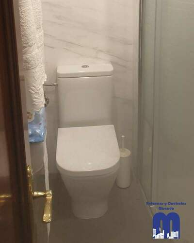 Reforma integral de baño moderno con ducha curva y revestimiento efecto mármol