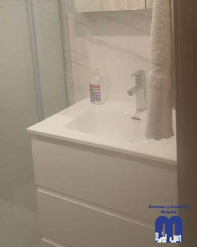 Reforma integral de baño moderno con ducha curva y revestimiento efecto mármol