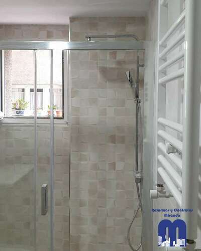 Reforma integral de baño moderno con acabados en madera y tonos piedra