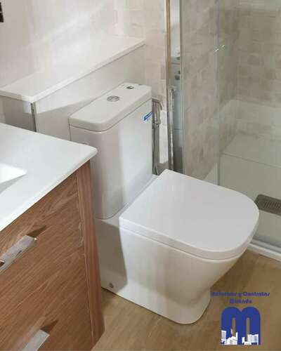 Reforma integral de baño moderno con acabados en madera y tonos piedra