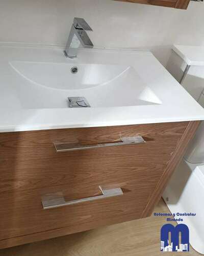 Reforma integral de baño moderno con acabados en madera y tonos piedra