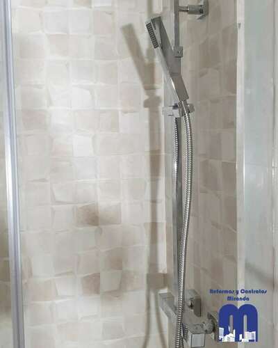 Reforma integral de baño moderno con acabados en madera y tonos piedra