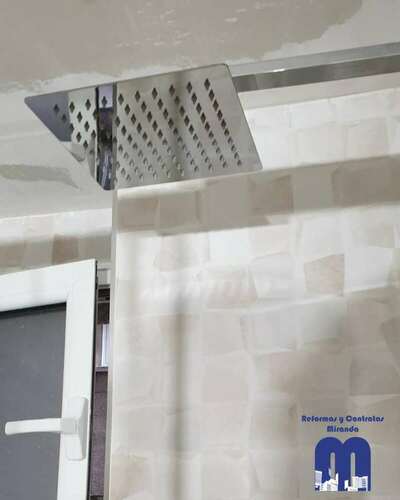 Reforma integral de baño moderno con acabados en madera y tonos piedra