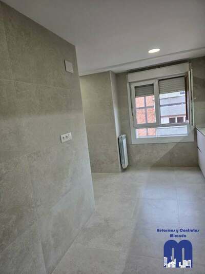 Reforma integral de cocina y cuarto de lavandería en Gijón con azulejo de gran formato, muebles en acabado madera y color viola, techos de pladur e iluminación LED integrada.