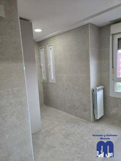 Reforma integral de cocina y cuarto de lavandería en Gijón con azulejo de gran formato, muebles en acabado madera y color viola, techos de pladur e iluminación LED integrada.