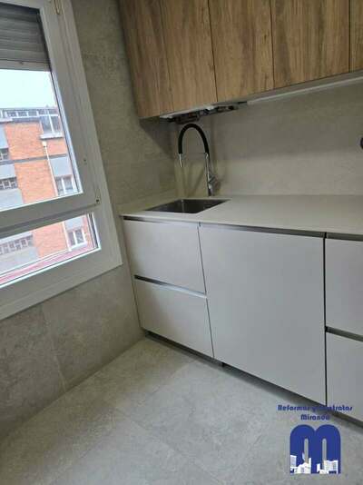 Reforma integral de cocina y cuarto de lavandería en Gijón con azulejo de gran formato, muebles en acabado madera y color viola, techos de pladur e iluminación LED integrada.