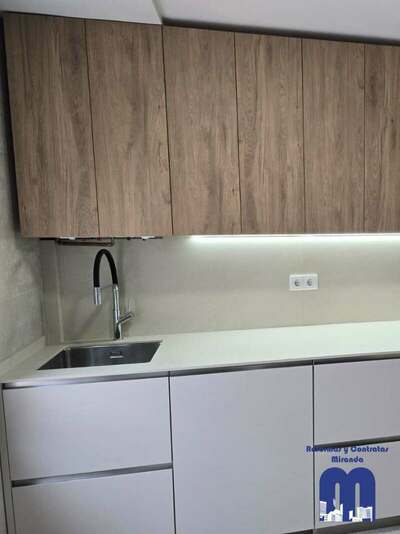 Reforma integral de cocina y cuarto de lavandería en Gijón con azulejo de gran formato, muebles en acabado madera y color viola, techos de pladur e iluminación LED integrada.