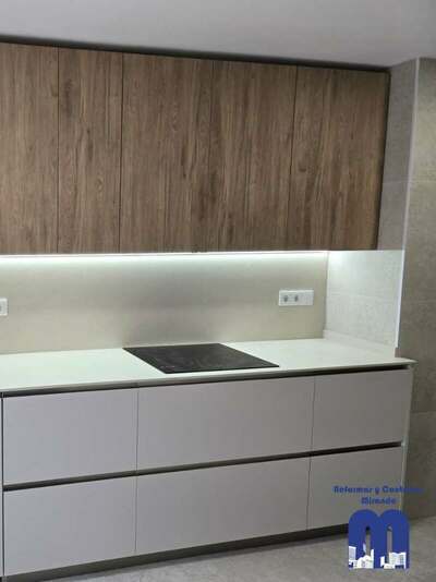 Reforma integral de cocina y cuarto de lavandería en Gijón con azulejo de gran formato, muebles en acabado madera y color viola, techos de pladur e iluminación LED integrada.