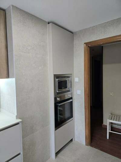 Reforma integral de cocina y cuarto de lavandería en Gijón con azulejo de gran formato, muebles en acabado madera y color viola, techos de pladur e iluminación LED integrada.