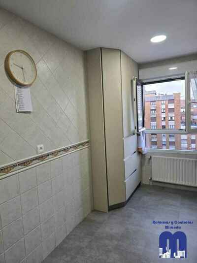 Reforma integral de cocina moderna con mobiliario en acabado tacto seda Fenix verde comodoro y beige, encimera y frente porcelánico Coverlam imitación mármol, suelo vinilico gris, fregadero bajo encimera y grifo monomando flexible de color negro.