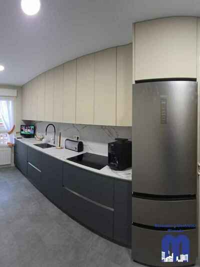 Reforma integral de cocina moderna con mobiliario en acabado tacto seda Fenix verde comodoro y beige, encimera y frente porcelánico Coverlam imitación mármol, suelo vinilico gris, fregadero bajo encimera y grifo monomando flexible de color negro.